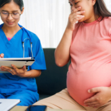 Asian doctor and nurse consult with pregnant woman on sofa, using ultrasound, health issues